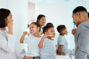 A family of four brushes their teeth together in the bathroom.